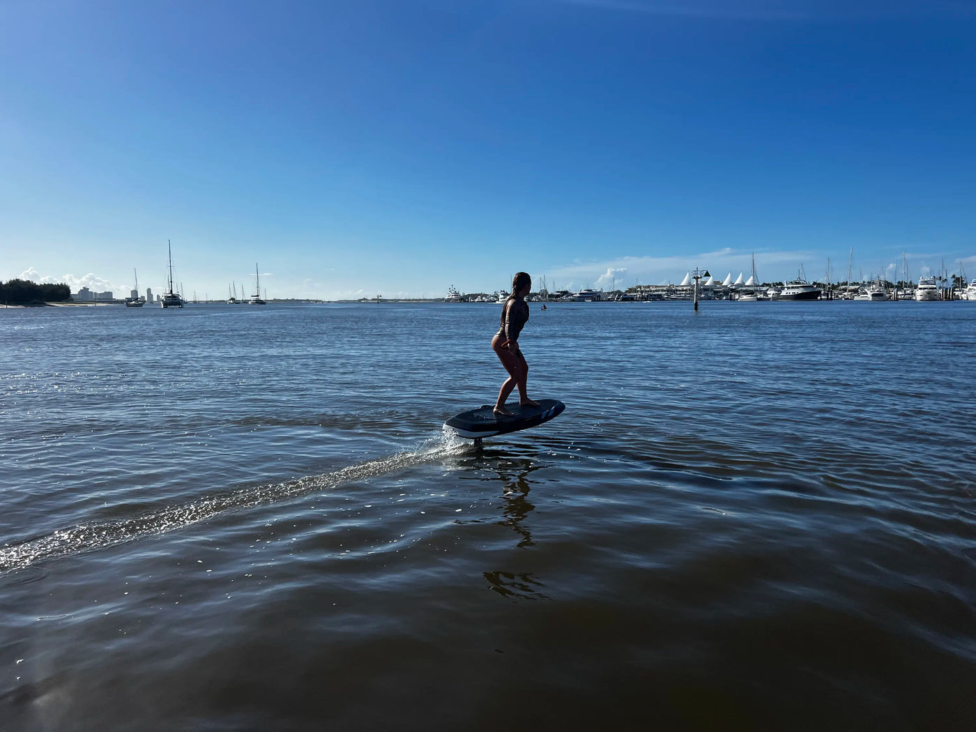 efoil vs hydrofoil comparison of a person riding an efoil on water with boats in the background
