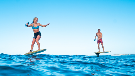 Two foilers riding above flat water with Waydoo FoilBoost foil assist systems